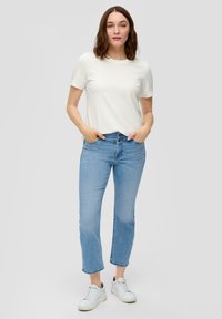 Witte T-shirt met korte mouwen, gecombineerd met lichtblauwe rechte jeans en witte sneakers. Eenvoudig ontwerp met een ontspannen pasvorm.