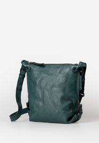 Borsa a tracolla in pelle verde acqua con una texture liscia, chiusura con zip, tracolla regolabile e dettagli in metallo. Presenta un design quadrato compatto.