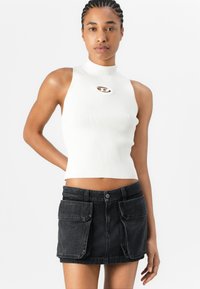 Balta ribota halter top ar priekšējo izgriezumu, kas apvienots ar melnu džinsu mini svārku ar lielām priekšējām kabatām un pogu aizdari.