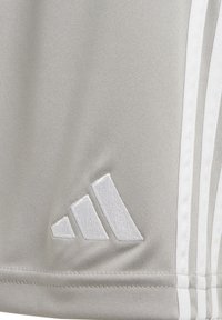Camiseta deportiva gris con una tela texturizada, que presenta acentos de tres franjas blancas de Adidas y un logo bordado en el lado inferior.
