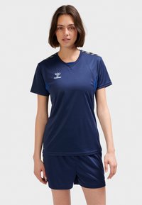 Marinblå sporttröja med korta ärmar och V-ringning, med blå accenter och texturerat mönster på axlarna. Matchas med matchande shorts.