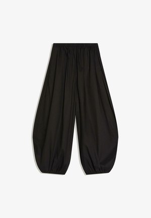 Pantalon noir ample avec taille élastiquée froncée et bas élastiqués, créant une silhouette ballon.