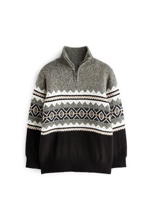 Sweter z półzamkiem przy kołnierzu w szaro-czarno-białej kolorystyce z geometrycznymi i zygzakowymi wzorami na piersi i rękawach, noszony na zewnątrz.