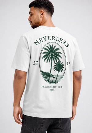Man facing sideways wears white t-shirt with green palm tree graphic and text "Nevertheless 2016 French Riviera" on the back.
