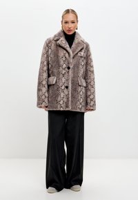 Textúrájú műszőrme kabát kígyómintázattal, kiemelkedő gallérral, három gombbal és két elülső zsebbel. Színpalettája bézs és barna.