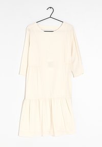 Vestido de marfil con mangas tres cuartos, un escote redondeado y un dobladillo de volantes en capas. Hecho de un tejido suave con una textura lisa.
