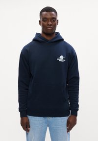 Hanorac cu glugă de culoare bleumarin, fabricat dintr-un material moale. Dispune de o buzunar frontal și un logo pe piept. Manșete și tiv ribate.