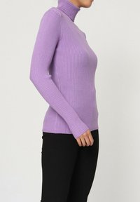 Pull en jersey côtelé violet avec col roulé, manches longues, coupe ajustée, texture douce et fentes sur les côtés ; associé à un pantalon noir.