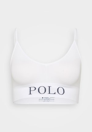 Bralette blanche avec des fines bretelles, texture côtelée et une large bande affichant « POLO » en bleu marine. Design simple et moderne adapté à une tenue décontractée.