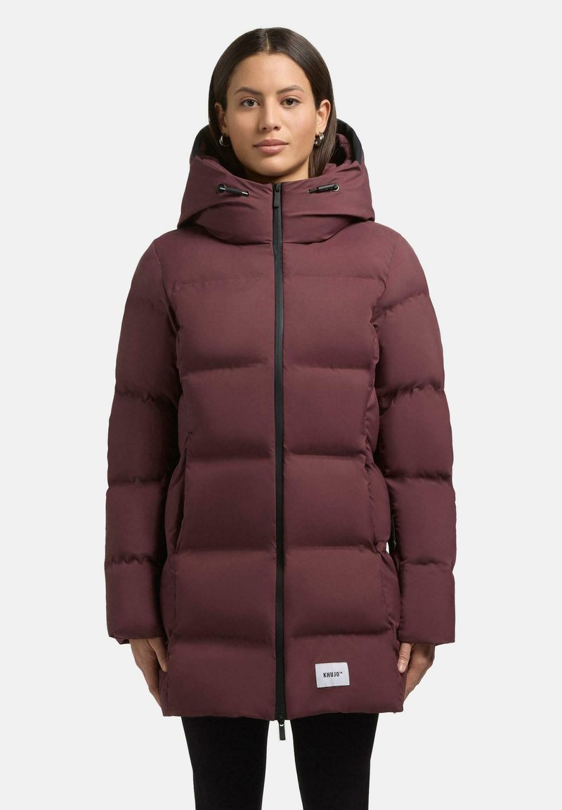 Giubbotto imbottito bordeaux con cappuccio, chiusura a zip e dettagli neri. Presenta un design trapuntato e tasche laterali. Cucitura del logo vicino all'orlo.