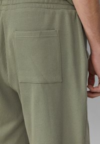 Olivgrüne, strukturierten Hosen mit einem Waffelmuster, ausgestattet mit einer Gesäßtasche und einem elastischen Bund.