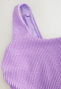 Lila strukturierte Bluse mit einem wellenförmigen Muster, ausgestattet mit verstellbaren Trägern und einem glatten Innenfutter. Nahaufnahme für Detailbetonung.