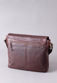 Brown leather messenger bag with a fold-over flap, a front zip pocket, and adjustable strap. Features textured surface and reinforced stitching.