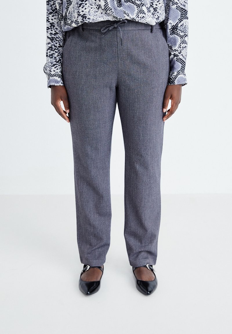 Grå strukturerade byxor med rak passform, dragsko i midjan och subtilt mönster. Matchas med svarta spetsiga ballerinas.