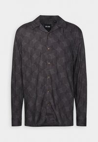 Chemise noire à manches longues avec boutons, avec un motif abstrait façon labyrinthe sur toute la surface et un col pointu.