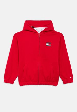Czerwona bluza z kapturem zapinana na zamek, z przednimi kieszeniami, elastycznymi mankietami oraz naszywką z logo Tommy Hilfiger na lewej piersi i rękawie.