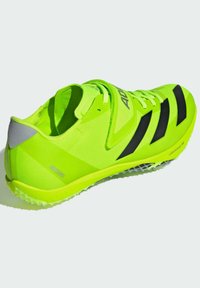 Neon green athletic shoe with a mesh upper, black stripes, and a reflective grey accent. Features a textured sole with spikes for traction.