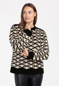 Zwart en crèmekleurig gebreid sweater met een textuur in het breiwerk, ronde halslijn en geribbelde manchetten en onderkant. Het materiaal lijkt dik en gezellig.