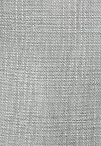 Textilstoff in Hellgrau, mit einer gewebten Textur und kleinen, einheitlichen Mustern, die eine gleichmäßige Oberflächenoptik bieten.