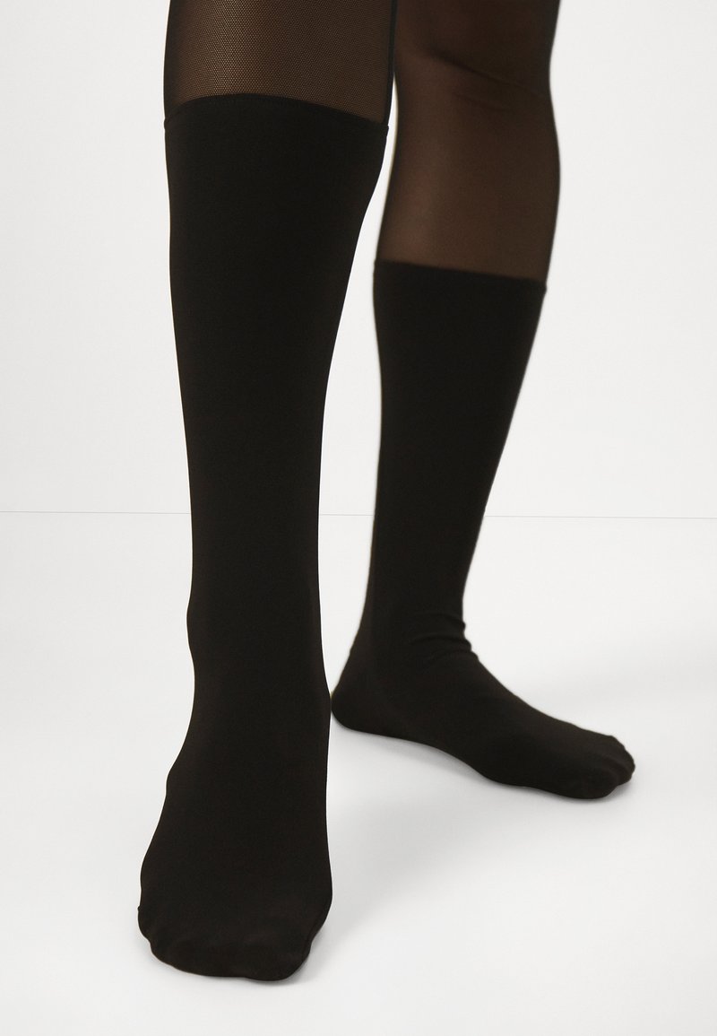 Schwarze knielange Socken aus dehnbarem Material, mit glatter Textur und ohne sichtbare Muster oder Hardware.