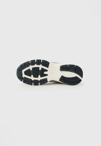 Talpa unei adidași cu un model de tălpă în alb și negru, conceput pentru aderență, prezentată pe un fundal simplu, deschis la culoare.