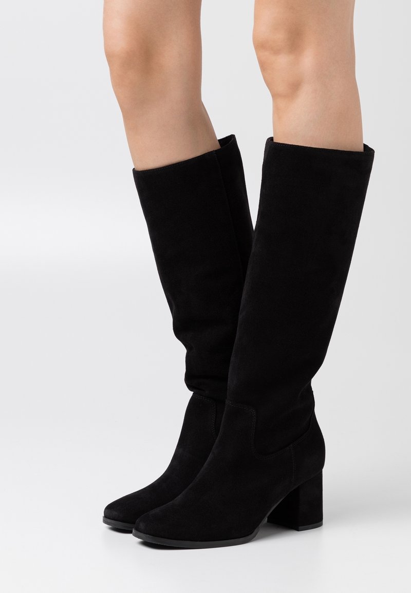 Botas altas de suede negro con un diseño ligeramente holgado, punta cuadrada y tacón grueso. Superficie lisa con detalles de costura.