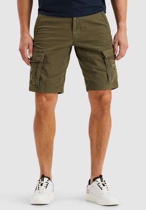 Cargo shorts i olivengrønt stof med flere sidelommer, kontrastsying og en afslappet pasform, kombineret med hvide sneakers.