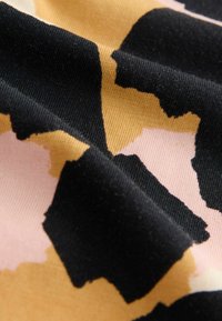 Bomullstyg med ett djärvt, abstrakt mönster i nyanser av svart, rosa och beige, med en slät, strukturerad yta.