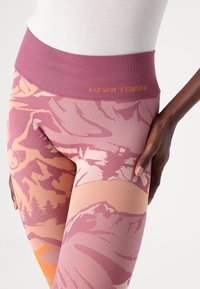 Hoch taillierte Leggings in einem pink- und orangefarbenen grafischen Muster, mit einem strukturierten Stoff und dem "Kari Traa" Logo am Bund.
