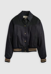 Mørk denimjakke med svart ullkrage, gullfargede trykknapper, elastiske ermer og midje med gule og marineblå striper.