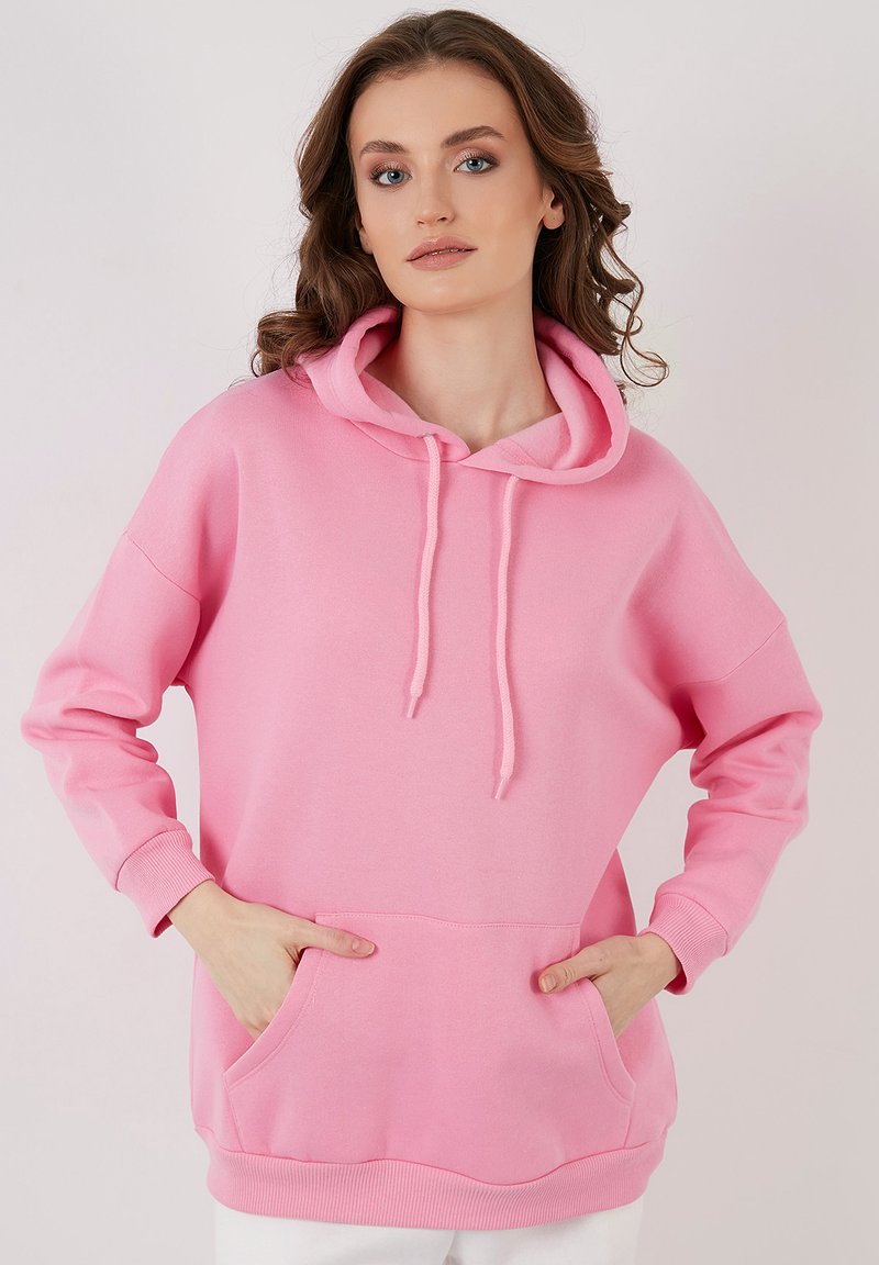 Felpa con cappuccio rosa realizzata in un morbido tessuto, dotata di tasca frontale, polsini a costine e cordoncino. Design casual e oversized.