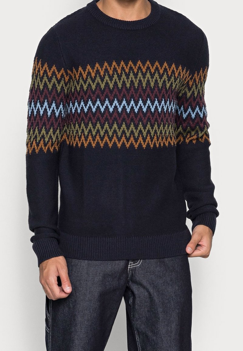 Pull marine avec un motif en zigzag multicolore. Confectionné en maille texturée, il présente un col rond ainsi que des poignets et un ourlet côtelés.