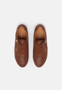 Brown leather sneakers featuring a white sole, lace-up design, and a side zipper for easy wear, with padded interior for comfort.