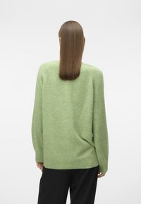 Grüner Wollpullover mit lockerer Passform, strukturierten Oberflächen, weiten Ärmeln und rundem Ausschnitt. Die Rückansicht zeigt eine weiche, entspannte Silhouette.
