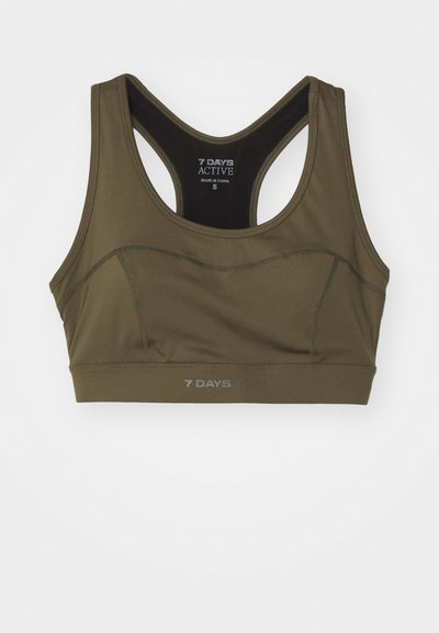 Olive green sports bra with a racerback design, made of smooth fabric. Features stitching details and printed logo at the bottom. Size: S.