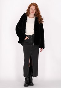 Sort faux fur jakke med hætte, hvid langærmet skjorte, sort denimnederdel med frontslids og sorte ankelstøvler. Glat tekstur, afslappet pasform.