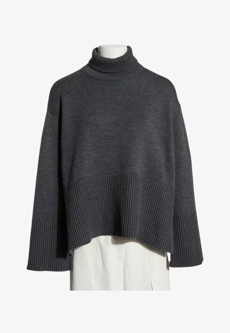 Pull à col roulé en maille côtelée gris foncé avec manches larges et coupe courte et carrée présenté sur un mannequin.