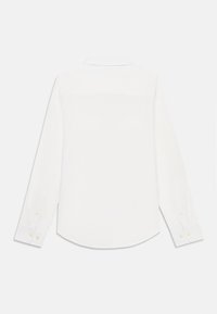 Cămașă albă cu mânecă lungă, cu guler, hem curbat și manșete butonate, realizată dintr-un material neted. Design simplu, fără modele sau grafice.