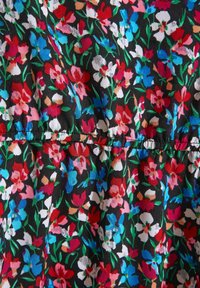 Tissu noir avec un motif floral dense en rouge, bleu, blanc, rose et vert, avec des fronces au centre.