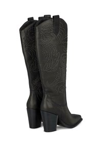 Las botas de cowboy de cuero negro presentan patrones intrincados de tachuelas, una punta afilada y un tacón robusto para mayor estabilidad. Textura de alto contraste.