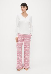 Balta garām piedurknēm henley krekls ar apaļu izgriezumu un pogu priekšu, komplektā ar rozā rakstainām pidžamas biksēm ar ziedu un dzīvnieku motīviem.
