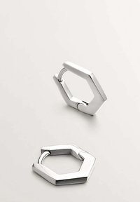Llaveros de metal en forma hexagonal, acabado plateado, textura suave, superficie ligeramente reflectante, con una bisagra para abrir y cerrar.