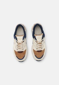 Sneaker mit weißem Leder-Obermaterial, braunen Wildlederakzenten, dunkelblauen Details und beigen Schnürsenkeln. Mit runder Zehenpartie und gepolsterter Sohle.