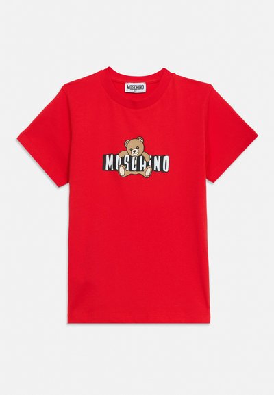 Red short-sleeve t-shirt with a teddy bear graphic holding text "MOSCHINO" on the front, round neckline, and label inside collar.