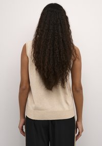Top sans manches beige en tricot doux avec un col rond et un ourlet côtelé. La vue de dos montre un tissu lisse sans motifs ni détails.
