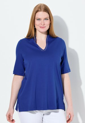 Haut à manches courtes bleu royal avec un col en V, orné de subtils accents en strass le long de l'encolure. Fentes sur les côtés pour plus de confort et de style.