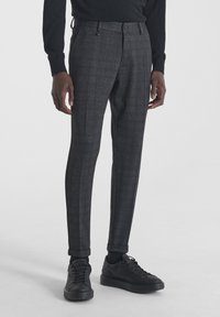 Slim fit sivi karirani hlače od teksturirane tkanine, s ravnim prednjim dijelom, petljama za remen i završenim manžetama, u kombinaciji s crnim tenisicama.