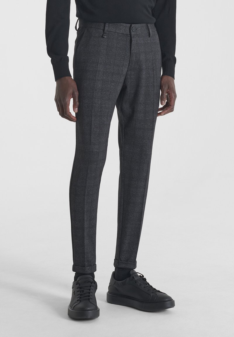 Slim fit sivi karirani hlače od teksturirane tkanine, s ravnim prednjim dijelom, petljama za remen i završenim manžetama, u kombinaciji s crnim tenisicama.
