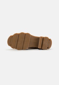 Suela de zapato de goma marrón con una superficie texturizada, estrías horizontales y un diseño de punta redondeada. Talla 37 indicada en la suela.