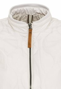 Gestepptes weißes Jacket mit Stehkragen, Front-Reißverschluss und braunem Leder-Reißverschlussanhänger. Strukturierte, kreisförmige Muster überall.